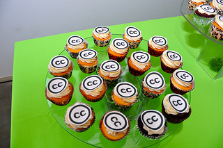 19 cupcakes with Creative Commons logos on top, arranged on a glass plate